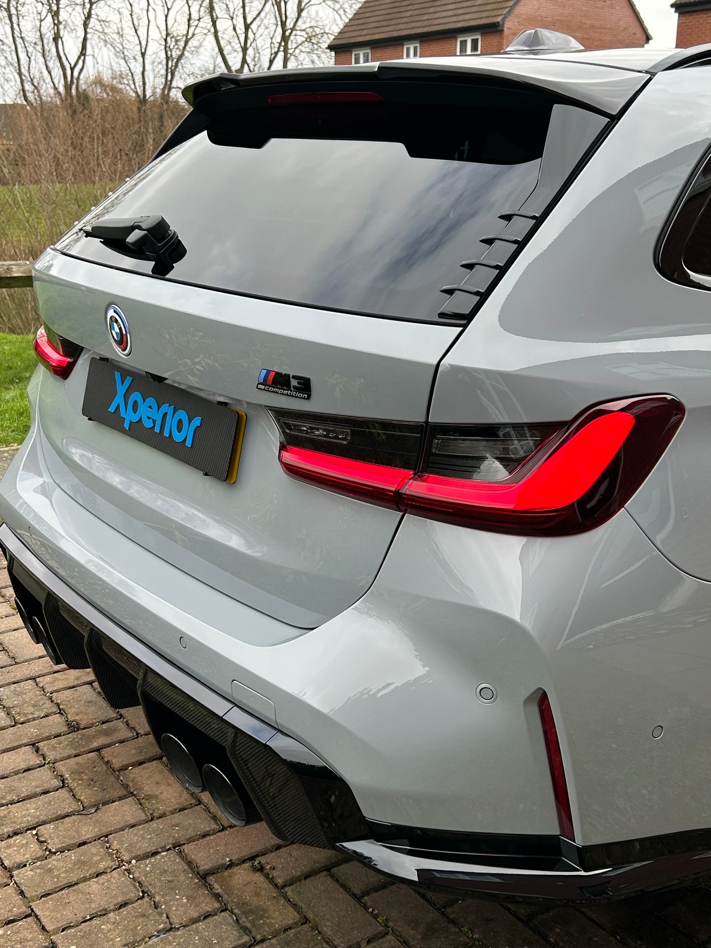 Detailed nardo grey BMW M3 Touring estate with an aggressive rear stance, carbon fiber accents, and LED taillights