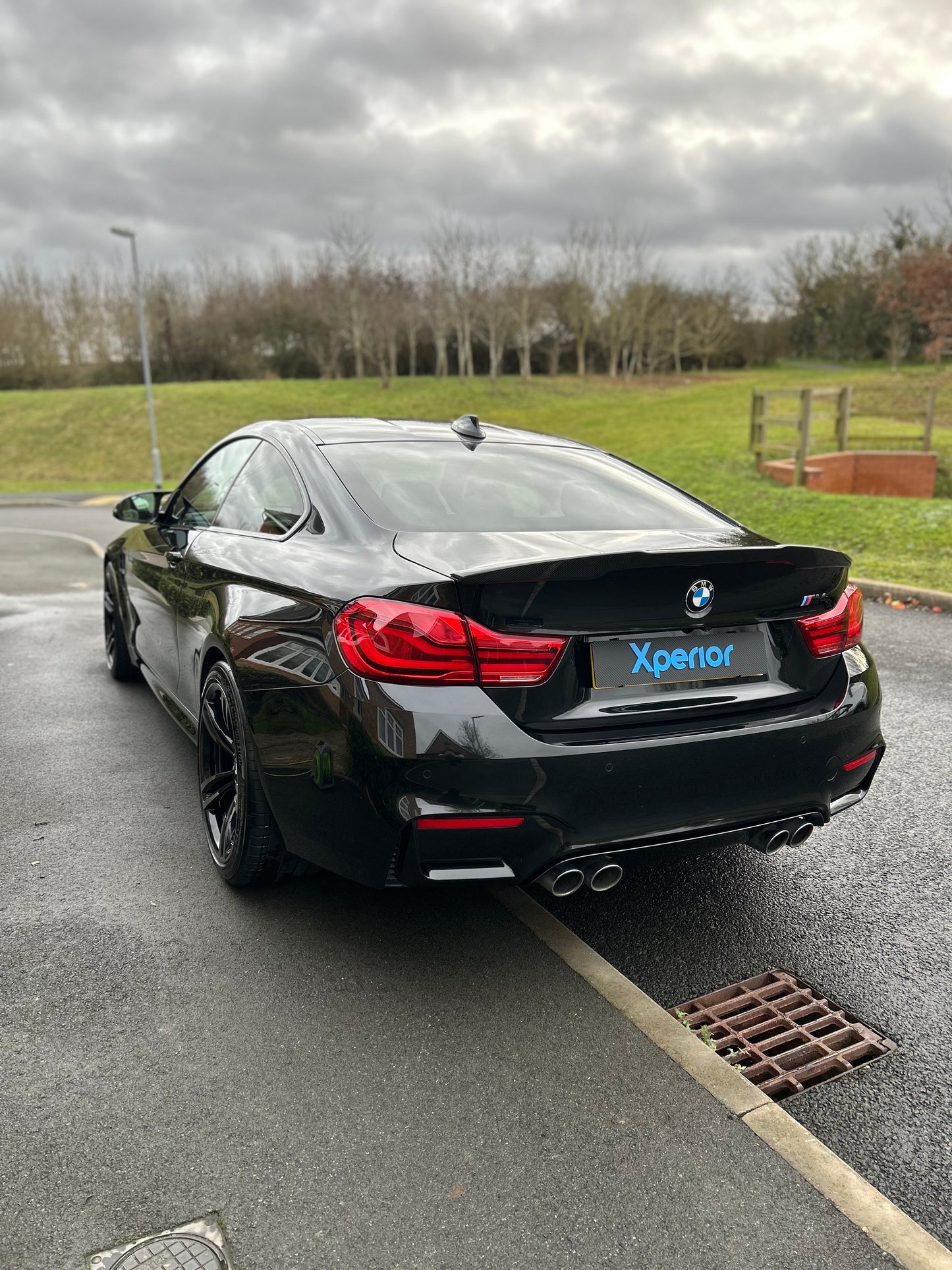 Rear view of a glossy black BMW M4, showcasing its flawless paint finish and professional detailing