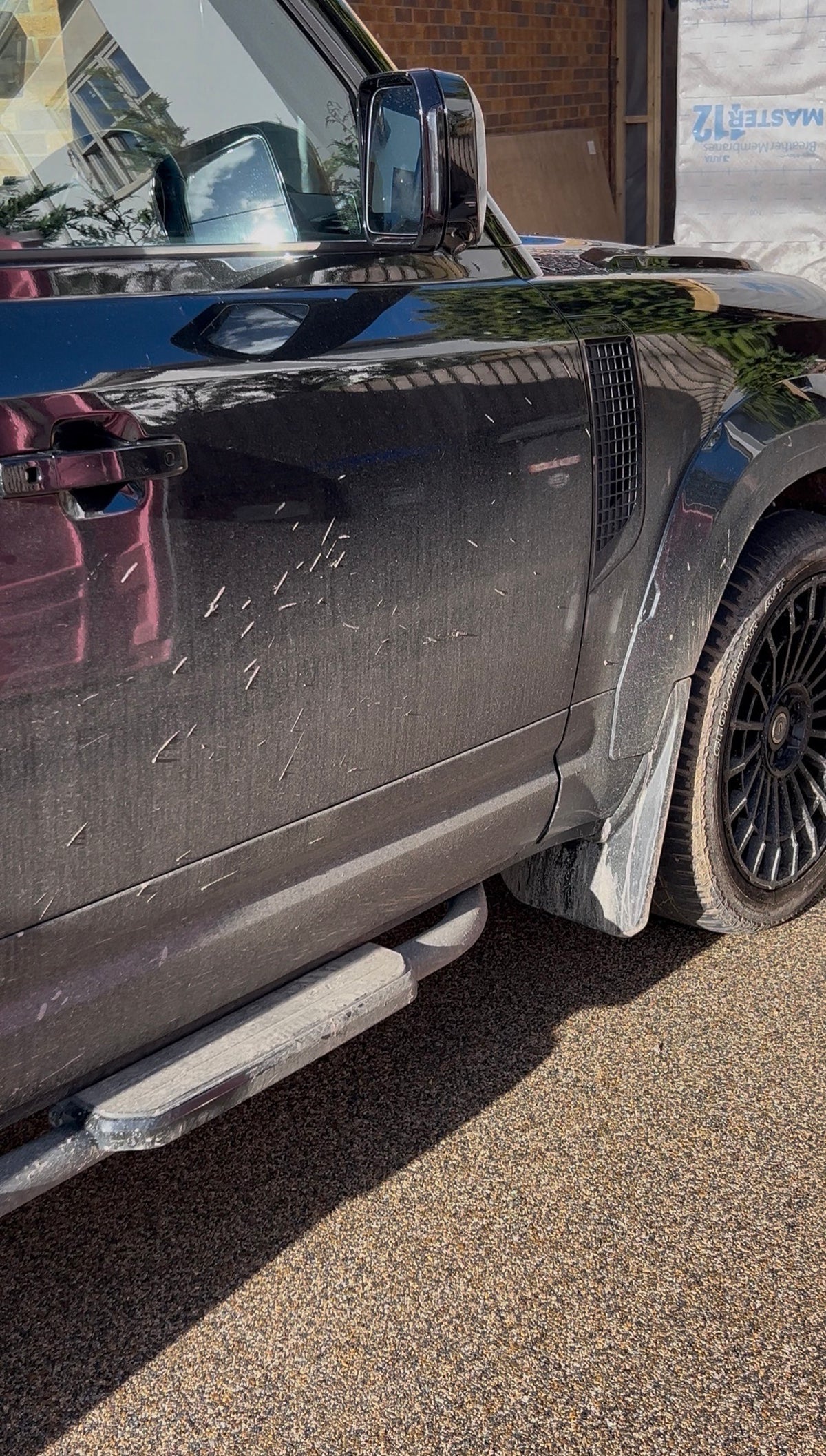 Side view of a black SUV with visible off-road grime and mud dried on the vehicle